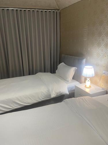 two beds in a hotel room with a lamp at Valley View Wadi Bani Khalid in Dawwah