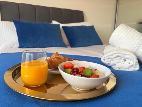 a tray with a bowl of fruit and a glass of orange juice at Centrally located 1bed near Windsor Castle Slough in Slough