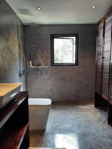 a bathroom with a toilet and a sink and a window at El Nido Villa Rentals in El Nido