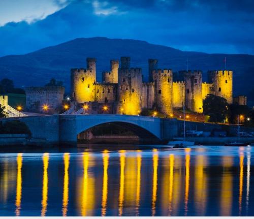 a castle with a bridge over a river with a castle at Denzels Den Apartment 2 in Llandudno Junction
