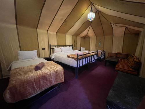a bedroom with two beds in a tent at Merzouga Majestic Camp in Merzouga