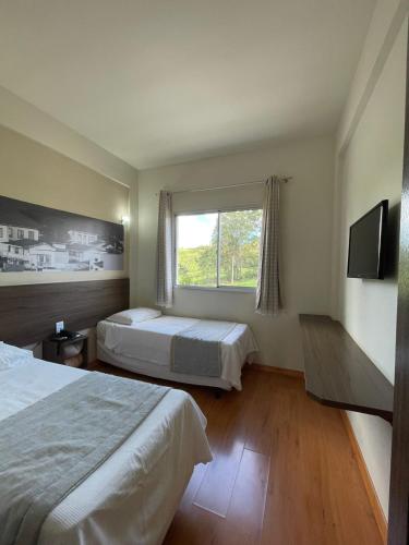 ein Hotelzimmer mit zwei Betten und einem Fenster in der Unterkunft Hotel 494 Oliveira-MG in Oliveira