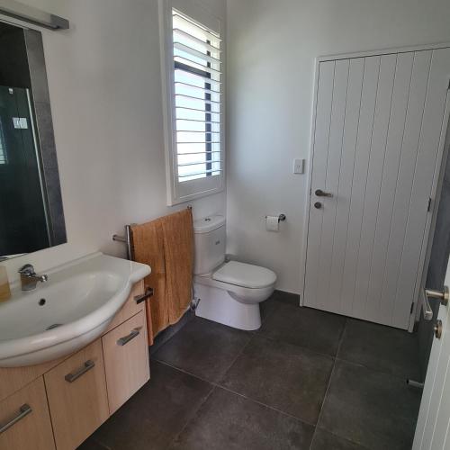 a bathroom with a sink and a toilet and a window at Sandspit Hideaway in Sandspit