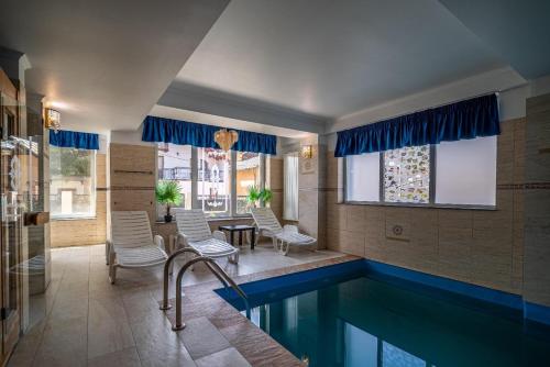 a swimming pool in a house with chairs and a table at Blue Hotel Boutique & Spa in Buşteni