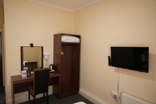 a hotel room with a desk and a flat screen tv at The Continental Hotel, Derby in Derby