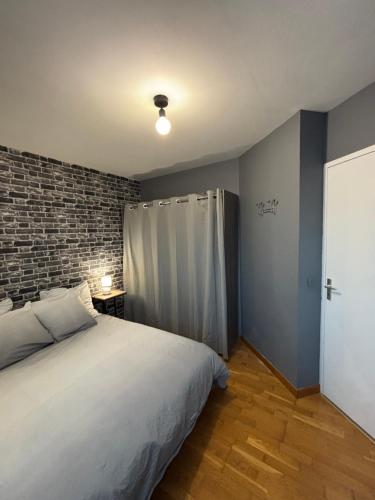 a bedroom with a bed and a brick wall at CNPE Bugey 10 MN - Aéroport LYS 18 MN in Pont-de-Chéruy