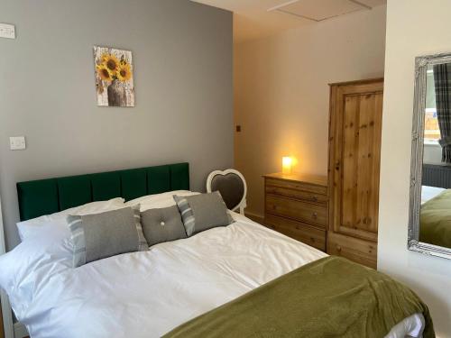 a bedroom with a large white bed with a green headboard at The Bungalow in Lichfield
