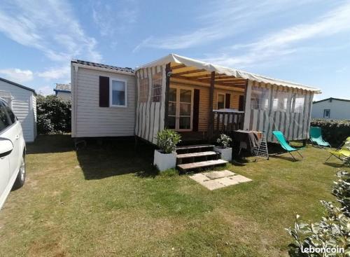 a tiny house with a porch and a table and chairs at Mobilhome Vendée Océan in Brem-Sur-Mer