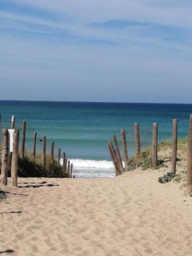 a wooden fence on a beach with the ocean at Mobilhome Vendée Océan in Brem-Sur-Mer
