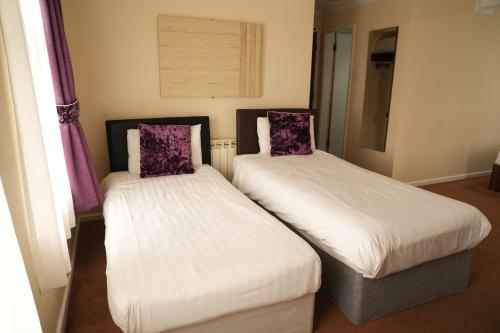 two beds in a room with purple curtains at The Continental Hotel, Derby in Derby