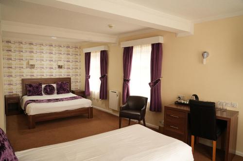 a bedroom with a bed and a desk with a chair at The Continental Hotel, Derby in Derby