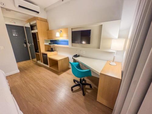 Zimmer mit einem Schreibtisch mit einem blauen Stuhl und einem Bett in der Unterkunft Moderno Flat no Gonzaga na quadra da Praia in Santos