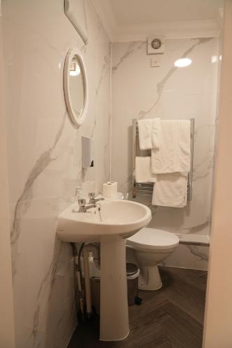 a white bathroom with a sink and a toilet at The Continental Hotel, Derby in Derby