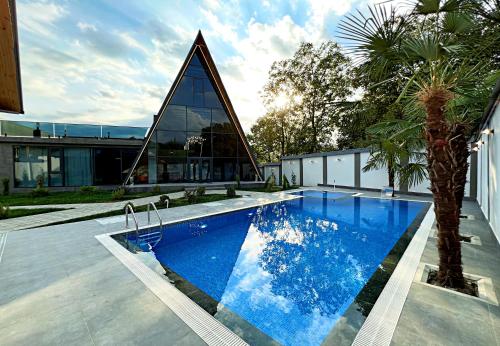 a house with a swimming pool in front of a building at Qafqaz Palm A-Frame Retreat in Gabala