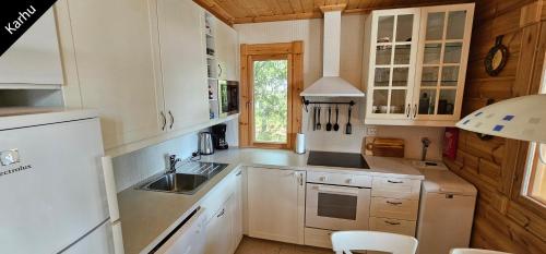 una cucina con mobili bianchi e un lavandino di Quiet Lakeside Forest Escape a Virasoja