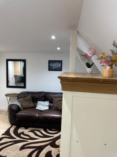 a living room with a brown leather couch at A Cosy and Spacious Studio Flat in Navestock