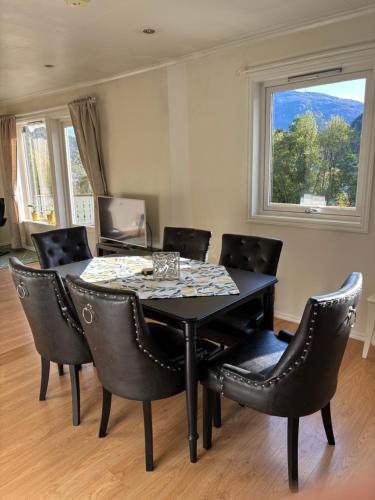 mesa de comedor con sillas negras y ventana en Solsiden apartment, en Sogndal