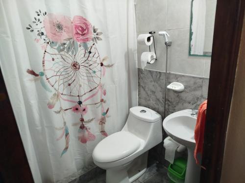 ein Badezimmer mit einem WC und einem Duschvorhang mit Blumen in der Unterkunft Departamento Manna in Alta Gracia