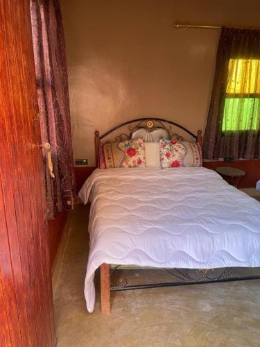 a bedroom with a bed with white sheets and pillows at Maison d'hôtes chez l'habitant Asfalou in Ouarzazate