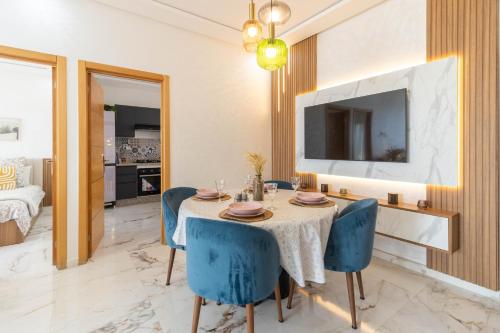 a dining room with a table and blue chairs at Fun and Sun - Appartement de luxe - Dahomey Beach - Bouznika in Bouznika