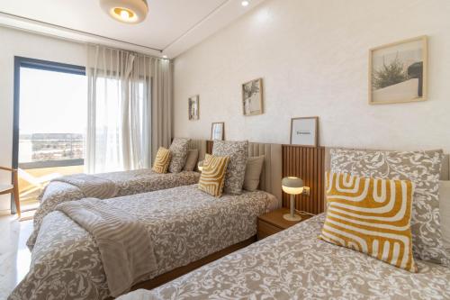 a bedroom with two beds and a window at Fun and Sun - Appartement de luxe - Dahomey Beach - Bouznika in Bouznika