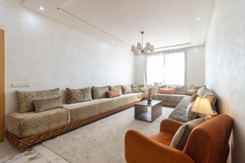 a living room with a long couch and chairs at Fun and Sun - Appartement de luxe - Dahomey Beach - Bouznika in Bouznika