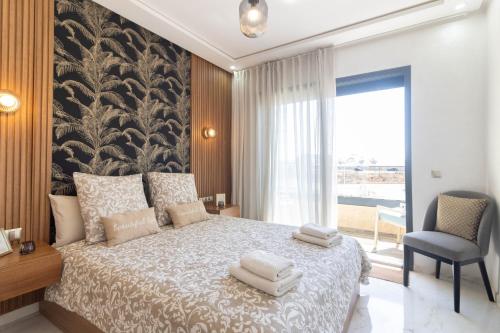 a bedroom with a large bed and a chair at Fun and Sun - Appartement de luxe - Dahomey Beach - Bouznika in Bouznika