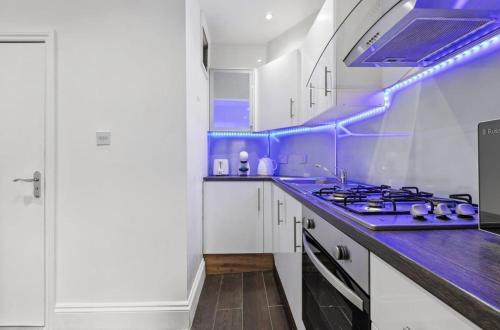 a kitchen with white cabinets and purple lighting at Amazing 1 Bedroom Flat in Central London in Moffat