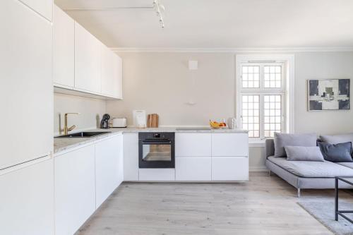 eine weiße Küche mit weißen Schränken und einem Sofa in der Unterkunft Skuteviken House in Bergen