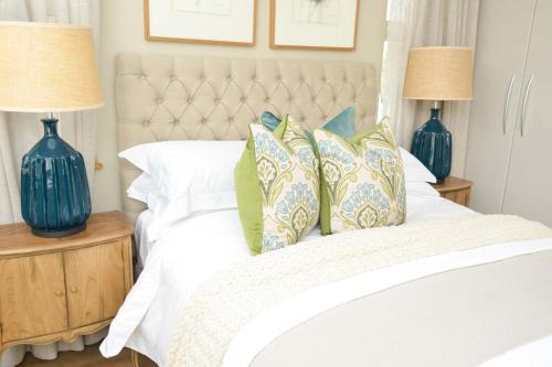a bedroom with a white bed with blue lamps at The Loft Apartment in Gaborone in Gaborone