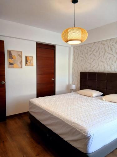 a bedroom with a large bed and a chandelier at Duplex Premium Cayma Céntrico in Cayma