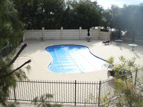 a swimming pool with tables and chairs and a fence at Unit 29 Ledge Point Village in Ledge Point