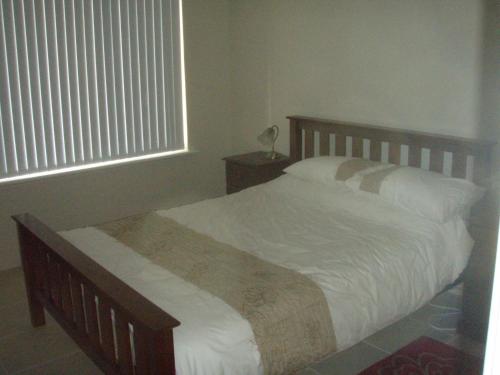 a bedroom with a bed with white sheets and a window at Unit 29 Ledge Point Village in Ledge Point