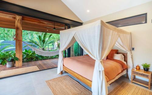 a bedroom with a canopy bed and a balcony at Balinese Inspired Luxury Villa in Playa Avellana