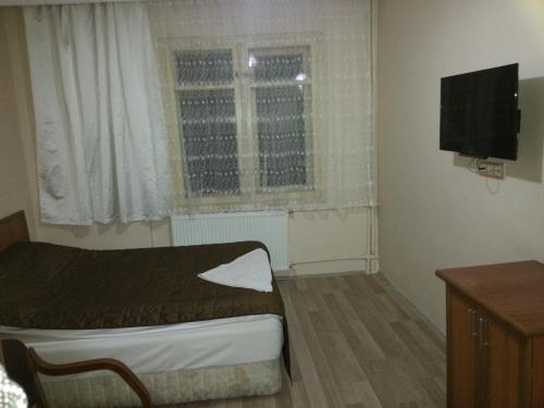 ein kleines Schlafzimmer mit einem Bett und einem TV in der Unterkunft Hotel Kervansaray in Erzurum