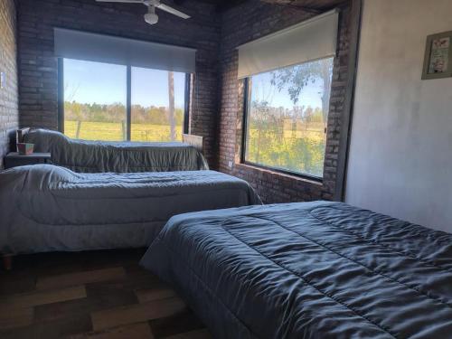 サン・ペドロにあるCasa de campoのベッドが2つと大きな窓がある寝室