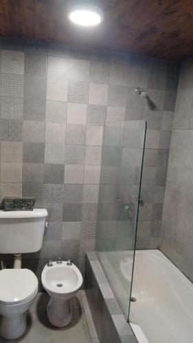 a bathroom with a toilet and a glass shower at Casa de campo in San Pedro