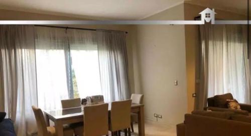 a living room with a table and chairs and a couch at Palm Hills The Village Gate New Cairo Nearly to AUC in Cairo