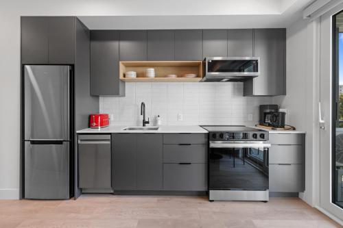 a kitchen with gray cabinets and a sink and a stove at Brand new suite downtown Kelowna - walk everywhere! in Kelowna