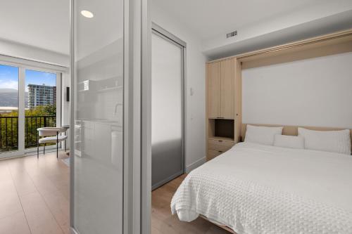 a bedroom with a white bed and a sliding glass door at Brand new suite downtown Kelowna - walk everywhere! in Kelowna
