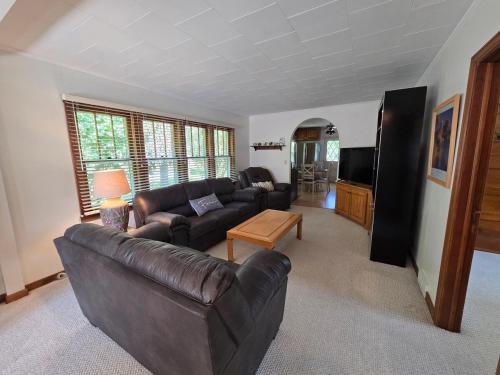 un salon avec un canapé en cuir et une télévision dans l'établissement Elena's Lake Cottage - A Cozy Lake Getaway, à Lake Geneva