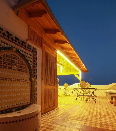 a patio with tables and chairs and a wooden door at Dar Rio Oro in Dakhla