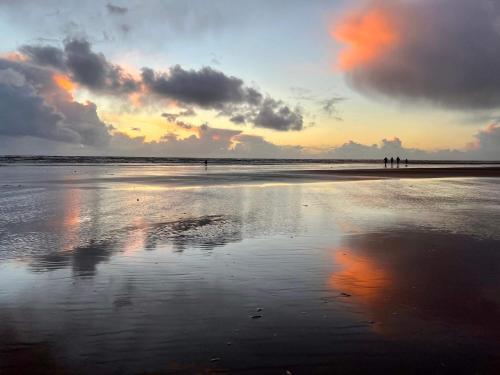 a group of people standing on a beach at sunset at 4 person holiday home in Fanø-By Traum in Fanø