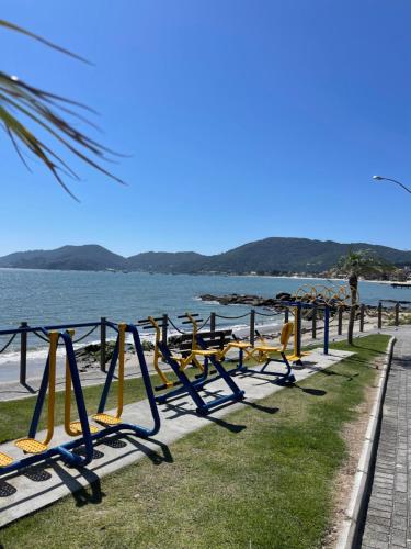 a row of swings on the beach near the water at Recanto Praia das Vieiras in Porto Belo