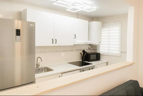 a kitchen with white cabinets and a stainless steel refrigerator at Apto La Justicia in Jerez de la Frontera