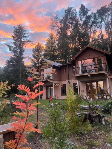 una casa nel bosco con un tramonto di CasaSur-37Robles-2 a Villa La Angostura