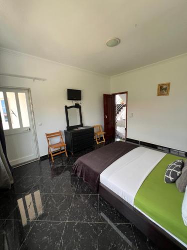 a bedroom with a large bed and a chair at Casa Miami in Tarrafal