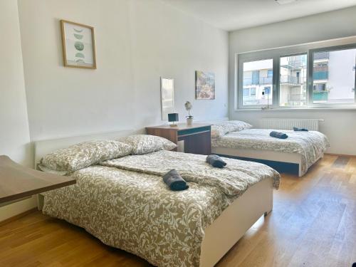a bedroom with two beds and a desk and windows at 140 m2 Spacious Apartment with Balcony & Parking in Vienna