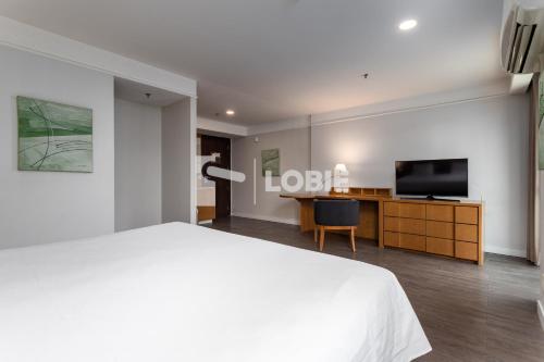 a bedroom with a white bed and a flat screen tv at Lobie Botafogo Privilege in Rio de Janeiro