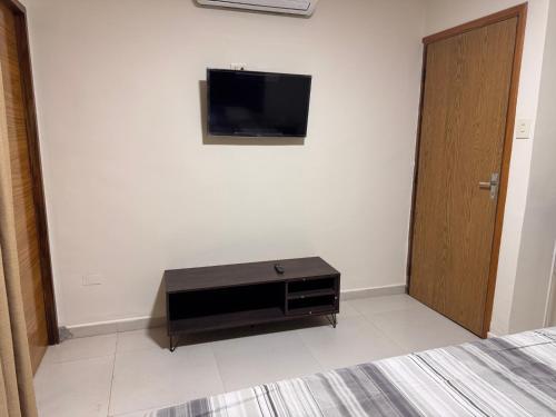 a room with a tv on the wall and a door at Sur Backpackers in Santa Cruz de la Sierra